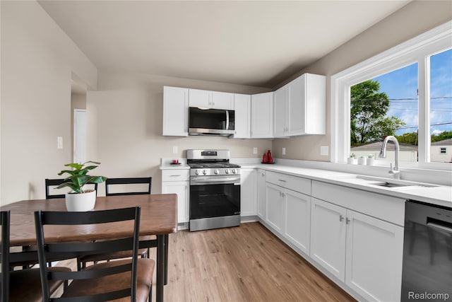23225 Beverly St, Saint Clair Shores, MI 48082 - kitchen with appliances with stainless steel finishes, a sink, light wood finished floors, light countertops, and white cabinets