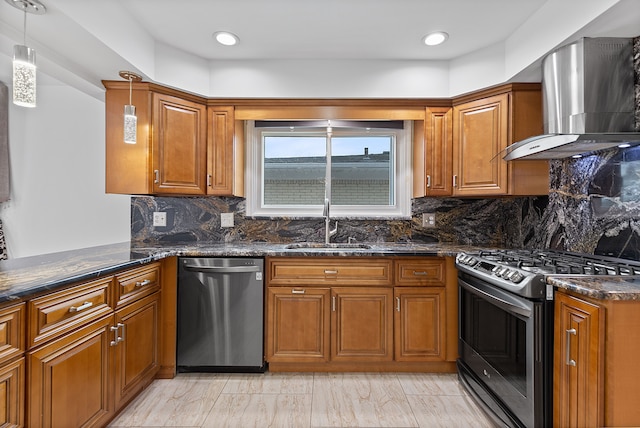 kitchen featuring wall chimney exhaust hood, sink, hanging light fixtures, dark stone counters, and stainless steel appliances