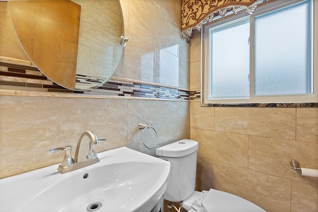 bathroom featuring toilet, sink, and tile walls