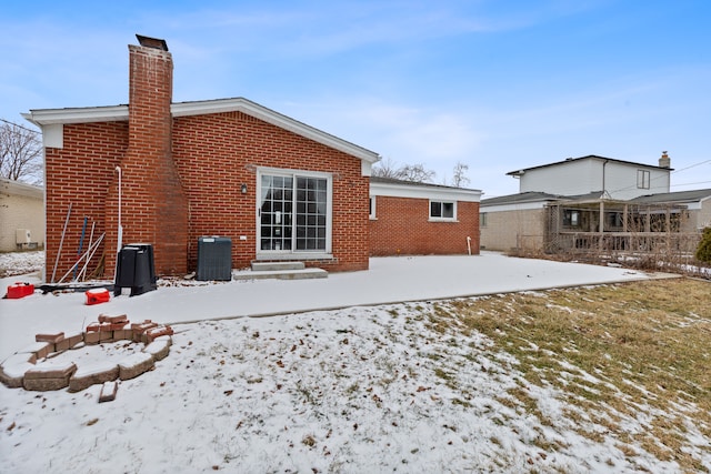 snow covered rear of property with central air condition unit