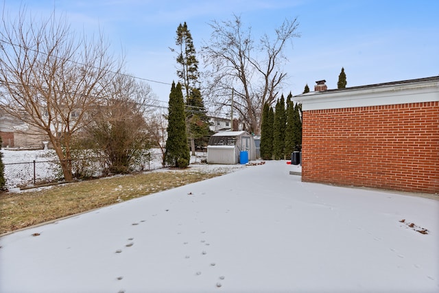 yard covered in snow featuring a shed