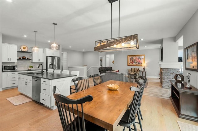 dining space with light wood-style floors, a fireplace, baseboards, and recessed lighting