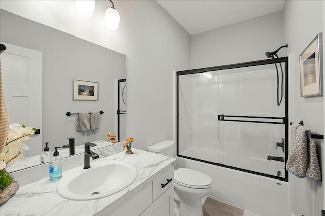 bathroom with toilet, shower / bath combination with glass door, and vanity