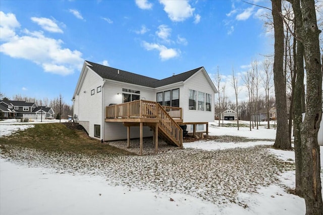 snow covered back of property featuring a deck and stairs