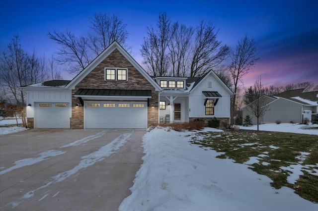 view of front of home with metal roof, stone siding, driveway, board and batten siding, and a standing seam roof