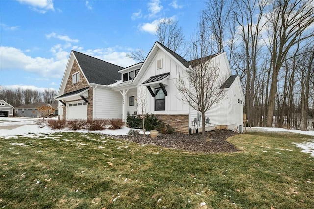 view of side of home with a garage, stone siding, a lawn, and board and batten siding