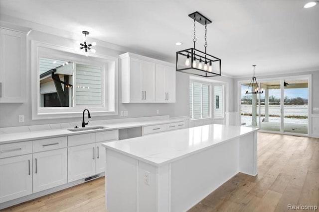 kitchen featuring white cabinetry, a kitchen island, sink, and pendant lighting