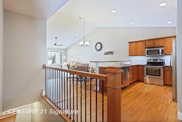 100 Tuscany Cir, Saginaw, MI 48603 - kitchen with appliances with stainless steel finishes, a peninsula, a sink, light wood-style floors, and brown cabinets