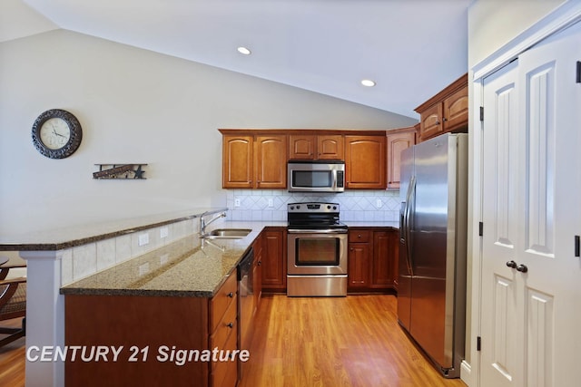 100 Tuscany Cir, Saginaw, MI 48603 - kitchen with stainless steel appliances, lofted ceiling, a peninsula, a sink, and dark stone countertops