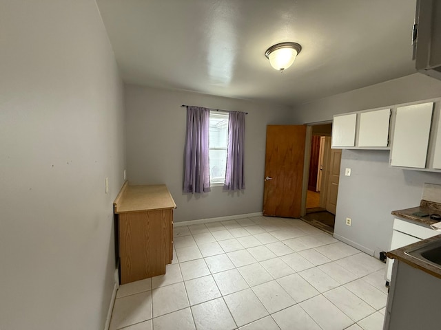 kitchen featuring baseboards, white cabinets, and light tile patterned flooring