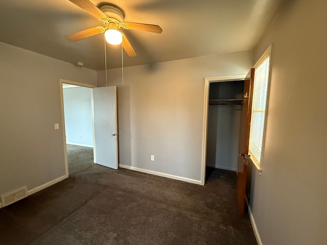 unfurnished bedroom featuring baseboards, visible vents, a ceiling fan, dark colored carpet, and a closet