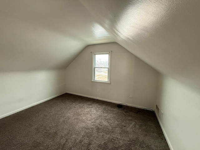 bonus room with lofted ceiling, dark carpet, a textured ceiling, and baseboards