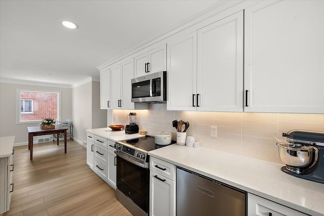 kitchen featuring white cabinetry, backsplash, appliances with stainless steel finishes, and light hardwood / wood-style flooring