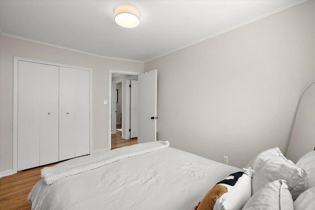 bedroom with light hardwood / wood-style flooring, crown molding, and a closet