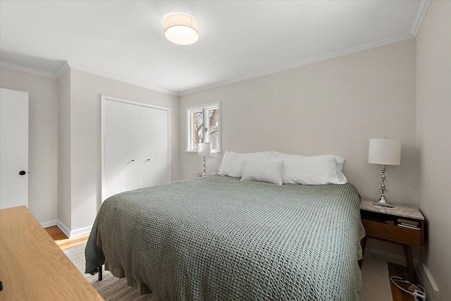 bedroom with light wood-type flooring, ornamental molding, and a closet