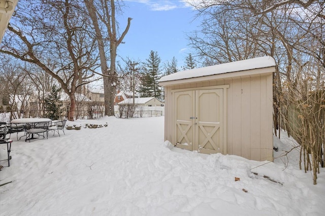 snowy yard featuring a shed