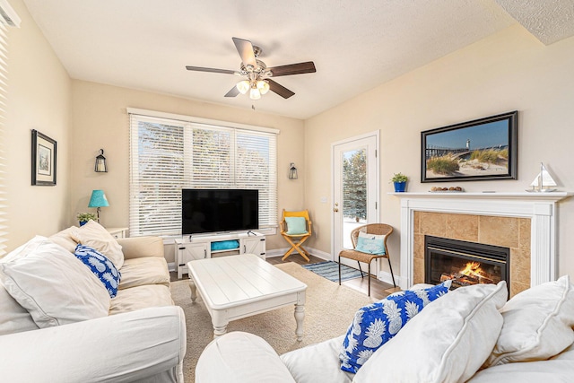 living room with a tiled fireplace, wood-type flooring, and ceiling fan