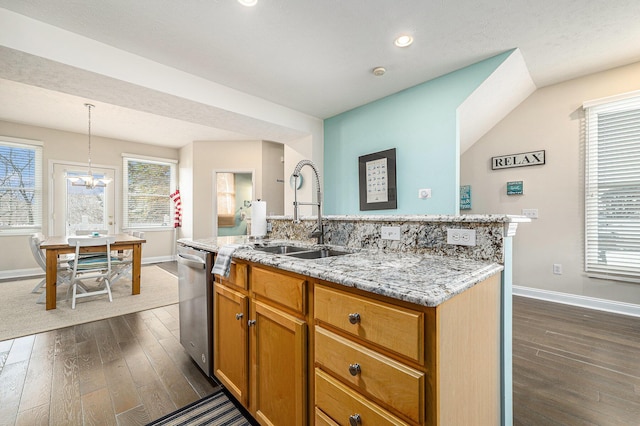 kitchen featuring sink, light stone counters, a center island with sink, dishwasher, and pendant lighting