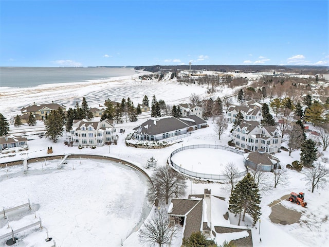 snowy aerial view with a water view and a beach view