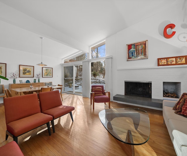 living room featuring beamed ceiling, high vaulted ceiling, a fireplace, and light hardwood / wood-style floors