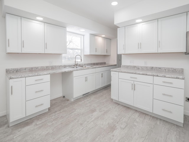 kitchen featuring white cabinetry, sink, and light stone counters