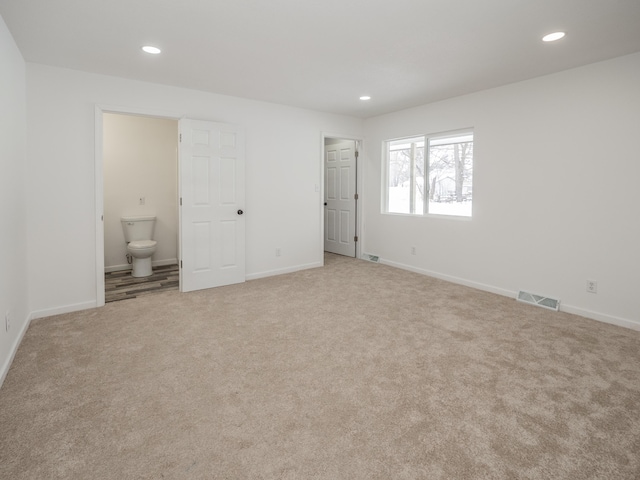 unfurnished bedroom with connected bathroom and light carpet