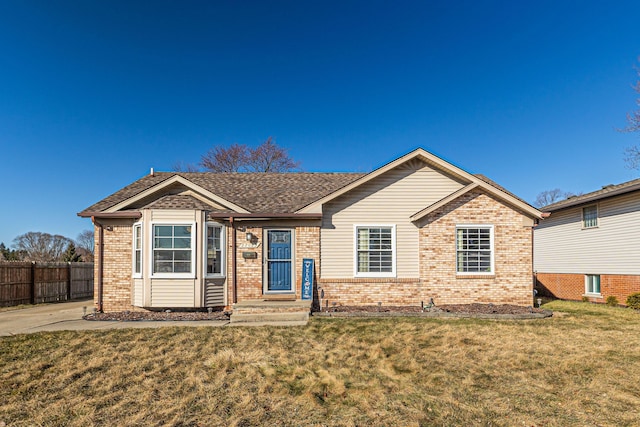 ranch-style house featuring a front yard, fence, brick siding, and roof with shingles