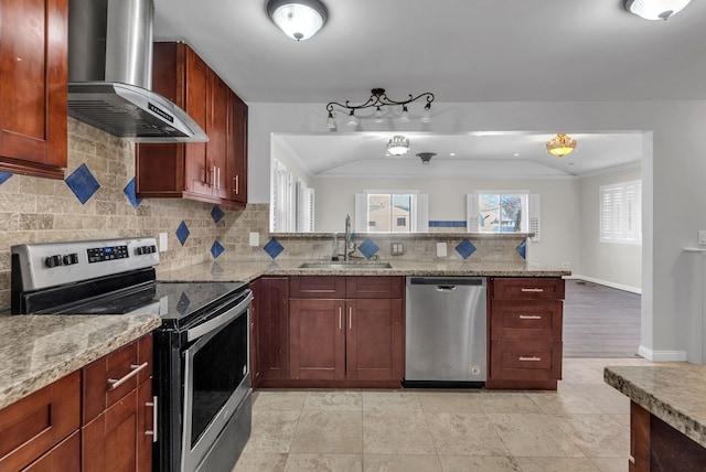 kitchen with stainless steel appliances, a sink, wall chimney range hood, light stone countertops, and a peninsula