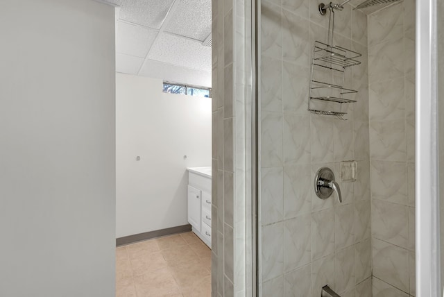 full bathroom featuring a paneled ceiling, a shower stall, vanity, and baseboards