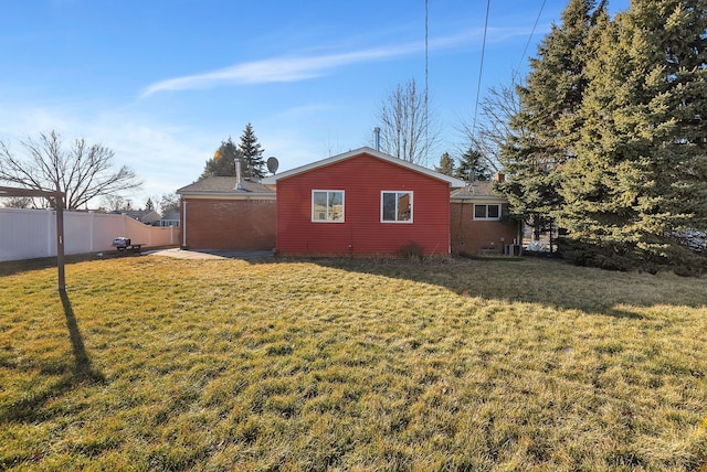 view of side of home featuring brick siding, fence, and a lawn