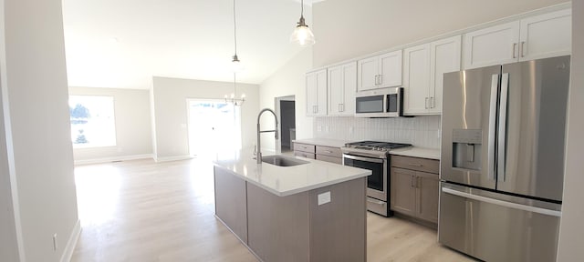 kitchen with stainless steel appliances, a kitchen island with sink, white cabinets, and decorative light fixtures