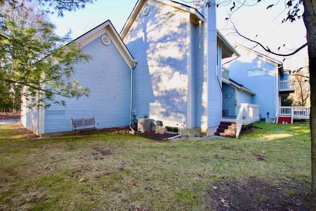 rear view of property featuring a chimney, a lawn, cooling unit, and a wooden deck