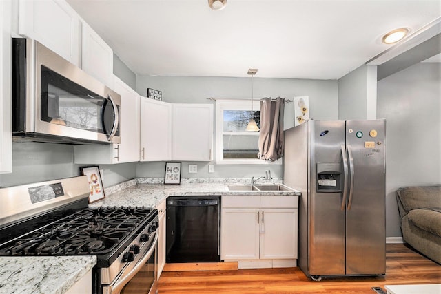 kitchen with white cabinetry, stainless steel appliances, decorative light fixtures, and sink