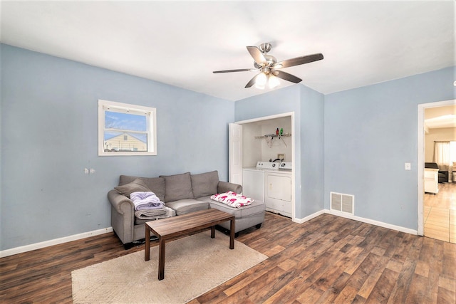 living room featuring washing machine and dryer, dark hardwood / wood-style floors, and ceiling fan