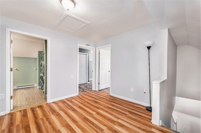 unfurnished bedroom featuring a baseboard heating unit and light wood-type flooring