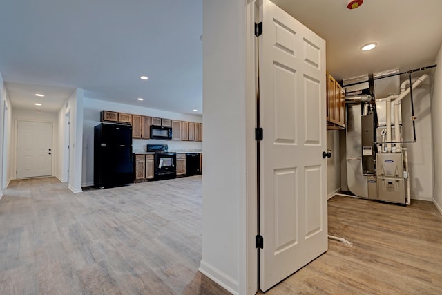 hallway featuring heating unit and light hardwood / wood-style flooring