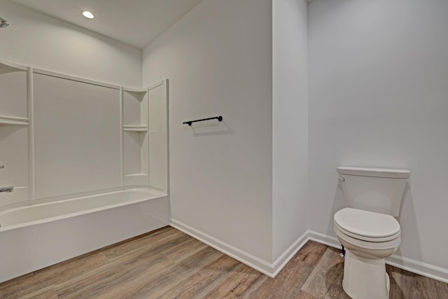 bathroom with wood-type flooring, tub / shower combination, and toilet