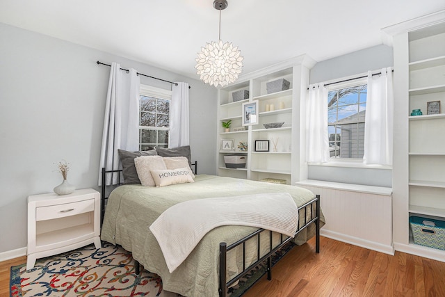 bedroom featuring wood-type flooring, multiple windows, and a notable chandelier