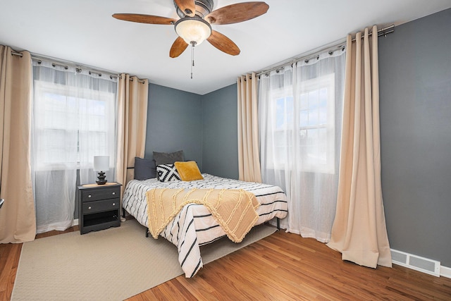 bedroom with ceiling fan, hardwood / wood-style floors, and multiple windows