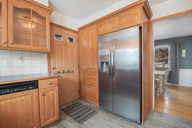 kitchen featuring stainless steel refrigerator with ice dispenser, paneled dishwasher, light hardwood / wood-style floors, and decorative backsplash