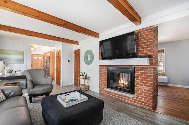 living room featuring a brick fireplace, beam ceiling, and wood-type flooring