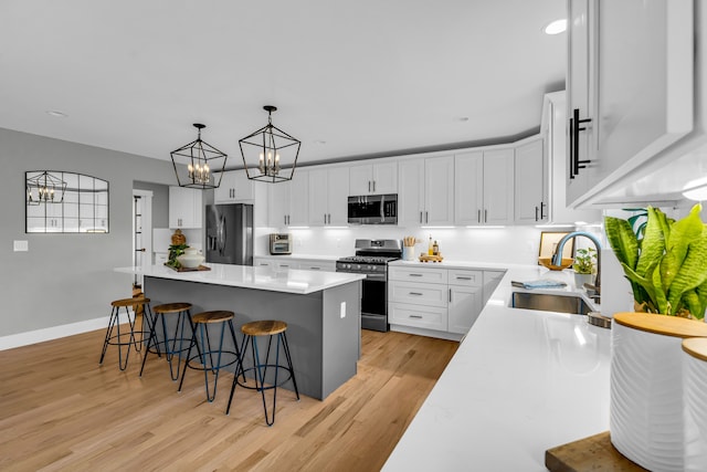 kitchen with appliances with stainless steel finishes, a center island, light countertops, and white cabinets