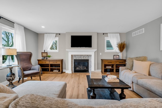 living room featuring baseboards, visible vents, a tiled fireplace, and wood finished floors