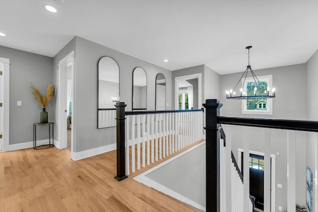 hallway with recessed lighting, an upstairs landing, baseboards, light wood-style floors, and an inviting chandelier