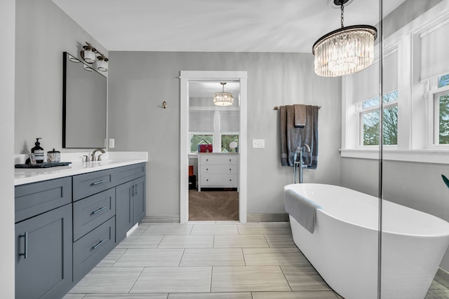 bathroom with a freestanding tub, baseboards, an inviting chandelier, and vanity