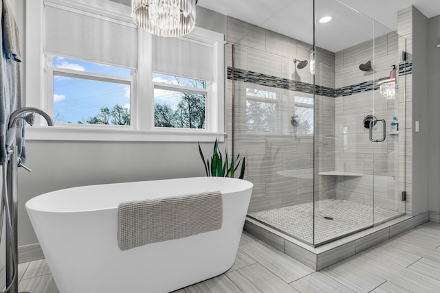 bathroom with a freestanding tub, a shower stall, and an inviting chandelier