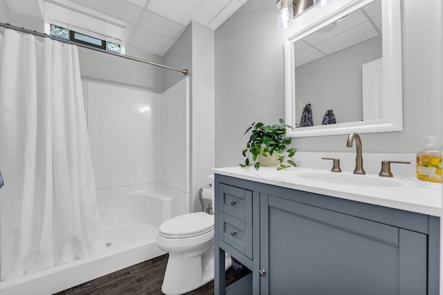 full bathroom featuring a paneled ceiling, a shower stall, toilet, and vanity