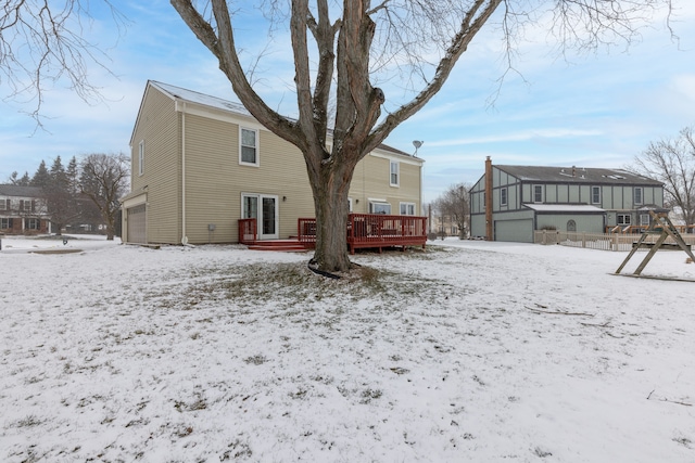 snow covered property featuring a wooden deck and a garage