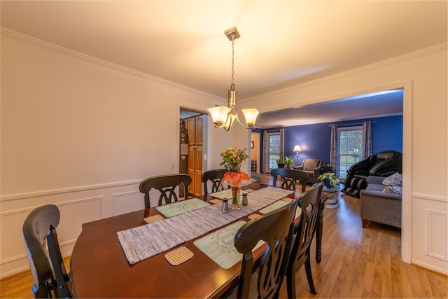 dining area featuring crown molding, light wood-type flooring, and a chandelier