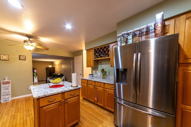 kitchen featuring stainless steel fridge with ice dispenser, light hardwood / wood-style flooring, ceiling fan, and a kitchen island